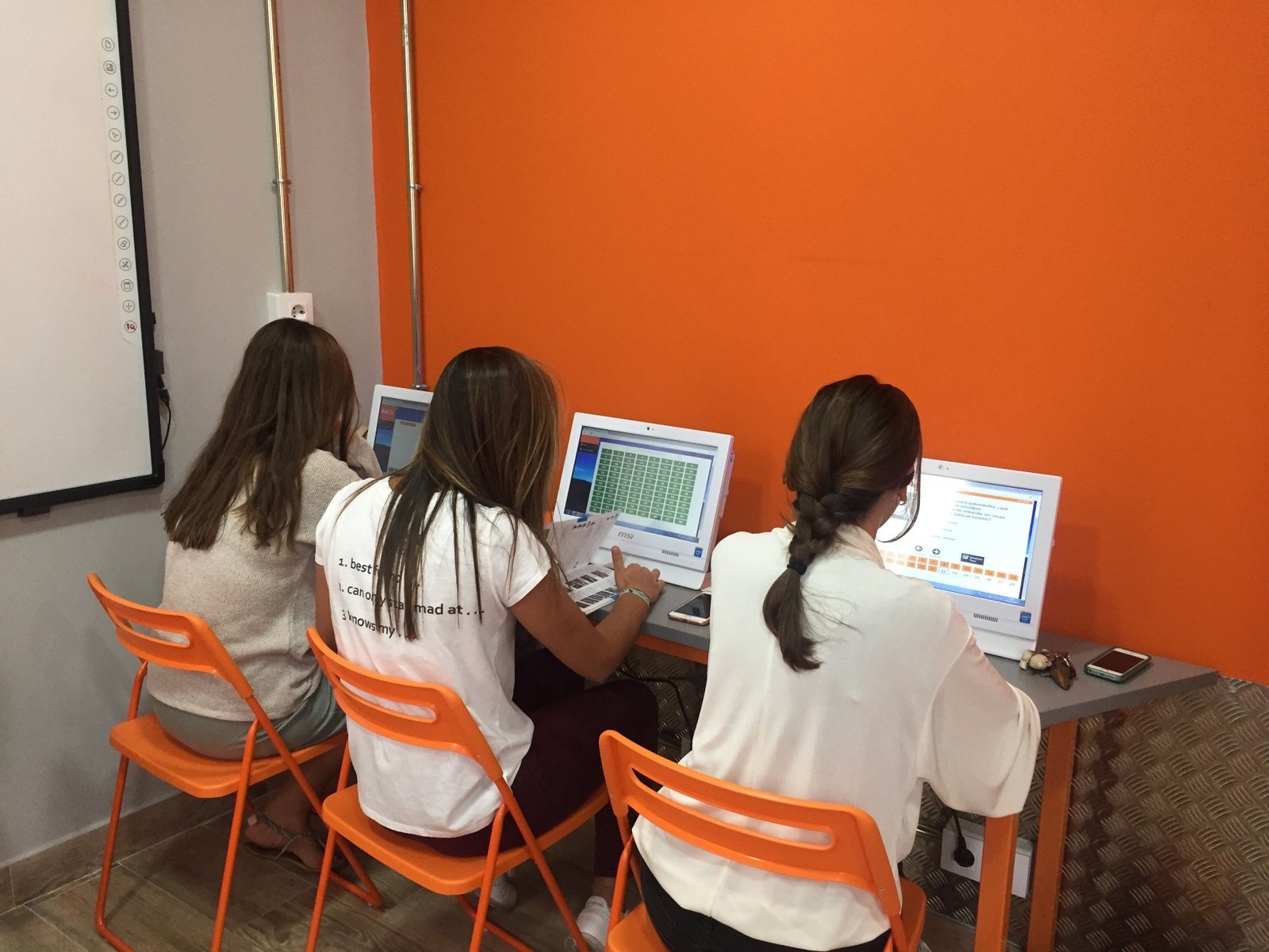 Alumnas jóvenes practicando tests en los ordenadores del aula de City Autoescuela