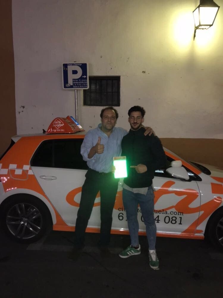 Manu con su profesor junto al coche de prácticas tras aprobar en City Autoescuela