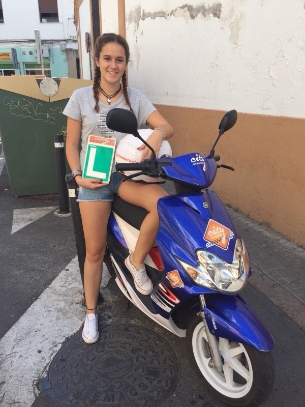 Alumna de City Autoescuela aprobada de la licencia AM, con la placa L sobre el ciclomotor Yamaha