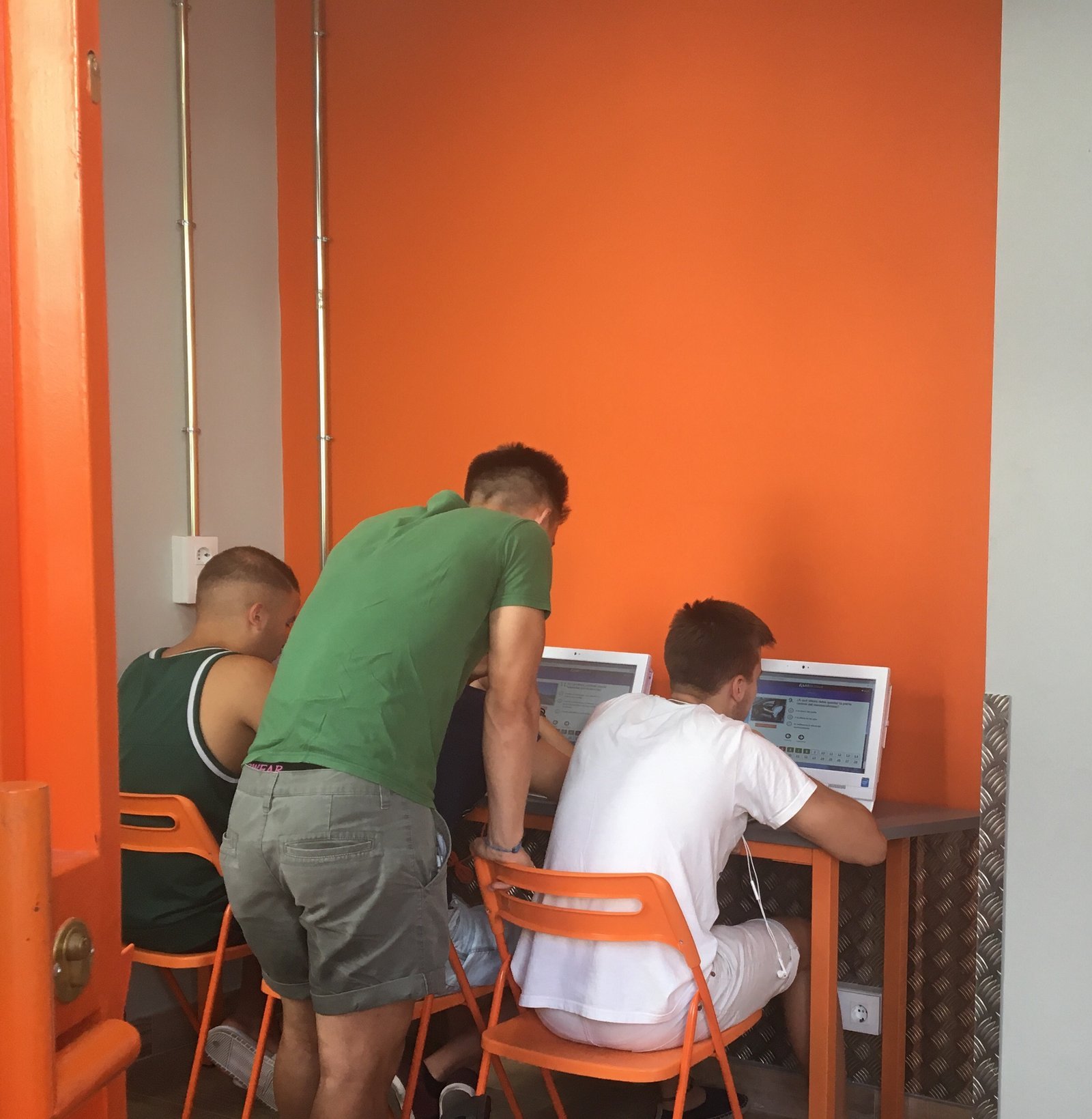 Profesor de City Autoescuela ayudando a dos alumnos con los tests en el aula