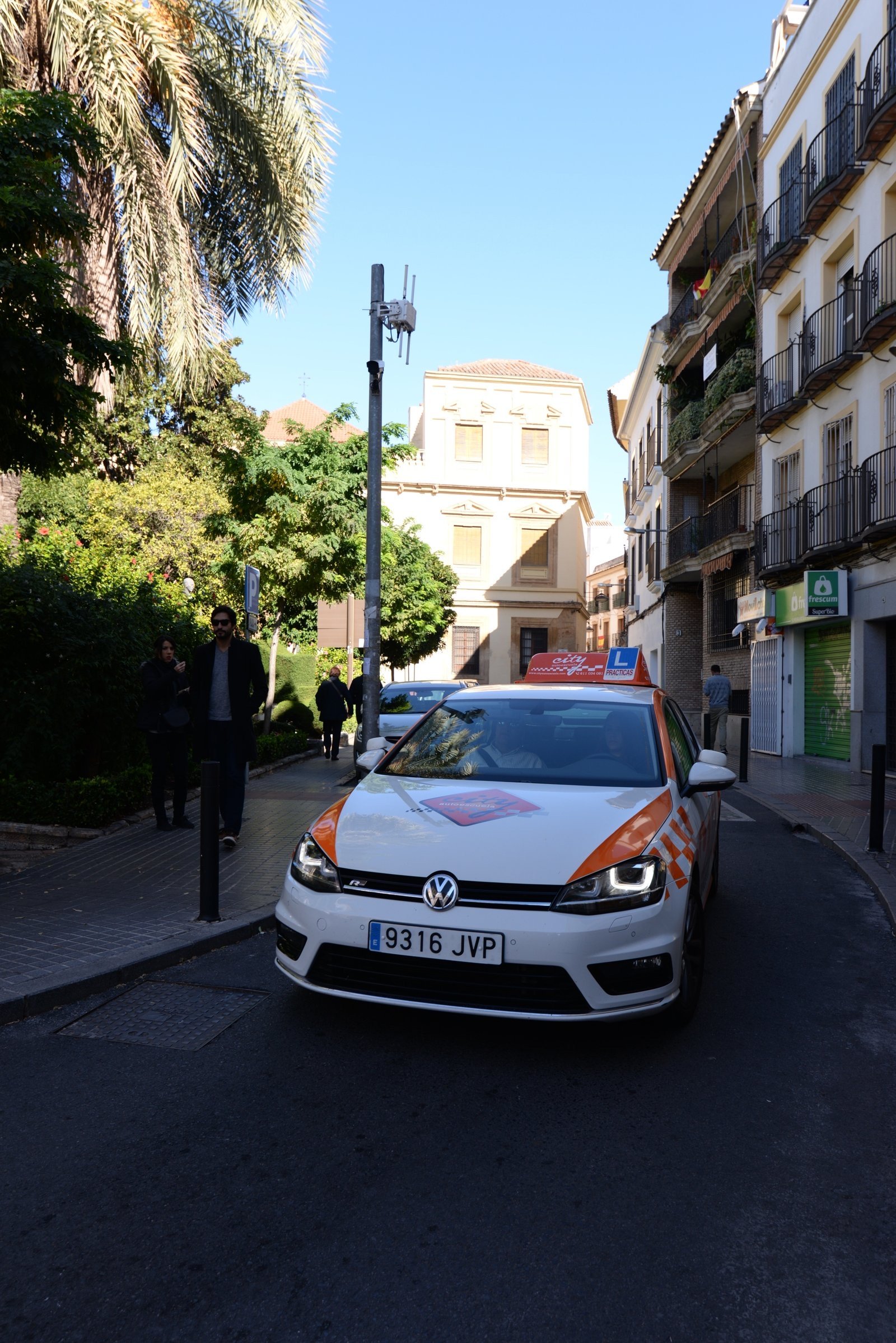 Coche de prácticas de City Autoescuela circulando por una calle estrecha del centro de Córdoba